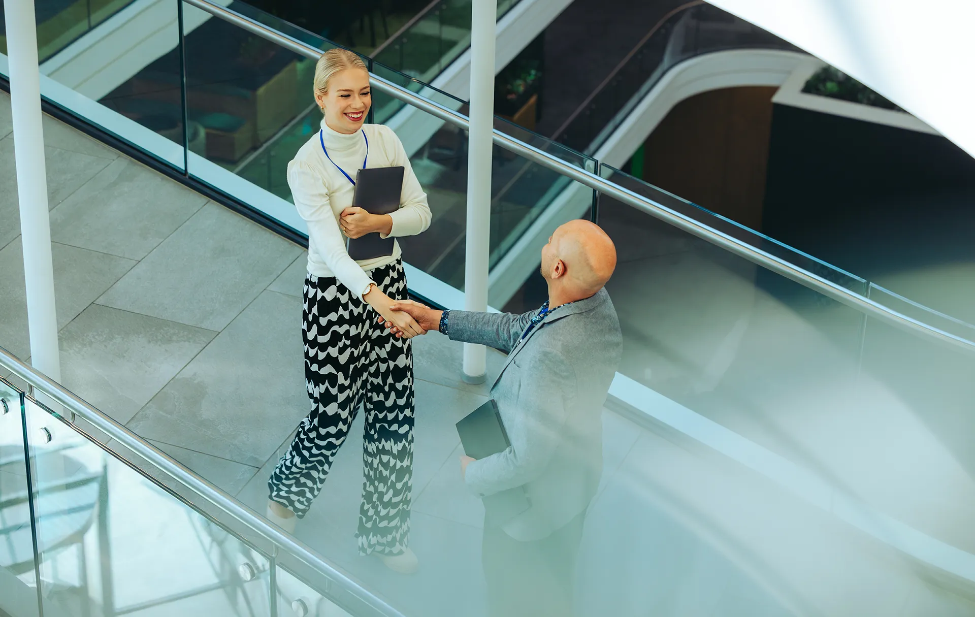 Zwei Personen begrüßen sich mit einem professionellen Handschlag in einer modernen Büroarchitektur. Symbolbild für Partnerschaft, Vertrauen und erfolgreiche Zusammenarbeit.